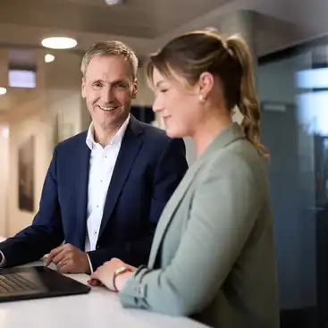 Eine Frau und ein Mann stehen an einem Tisch vor einem Laptop