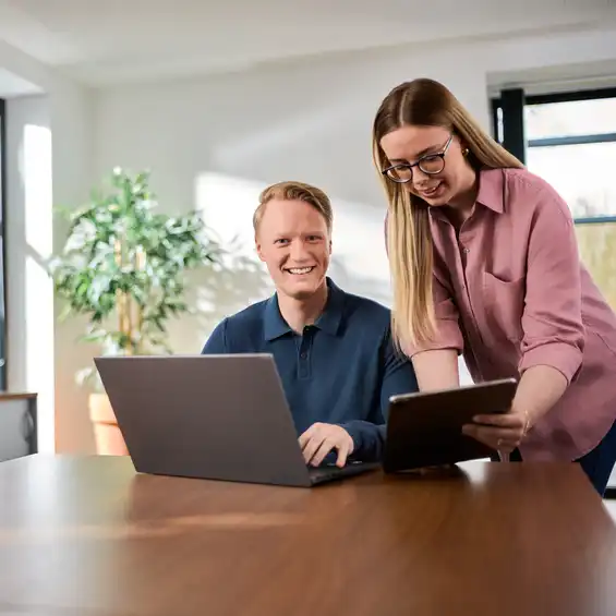 Ein Mann und eine Frau am Schreibtisch mit einem Tablet und Laptop